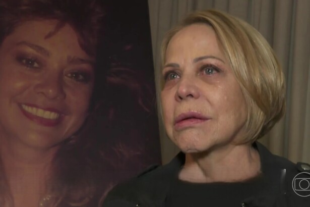 Claudete Troiano com lágrimas nos olhos em frente a um quadro com foto de Ione Borges no velório da apresentadora