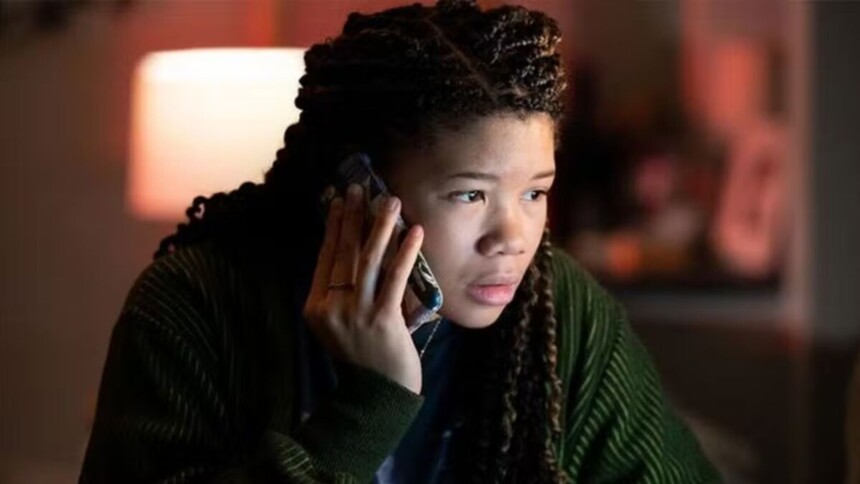 Atriz Storm Reid como June Allen, a protagonista do filme de suspense Desaparecida, falando ao telefone com expressão de preocupação em ambiente escuro