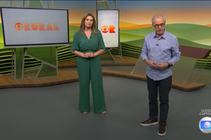 Cristina Vieira de vestido verde ao lado de Nélson Araújo que veste camisa clara e calça preta no cenário do Globo Rural