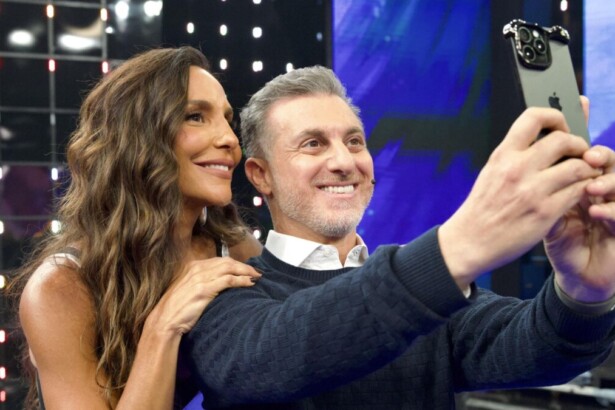 Cantora Ivete Sangalo e apresentador Luciano Huck tirando selfie no palco do programa Domingão com Huck, sorrindo para o celular