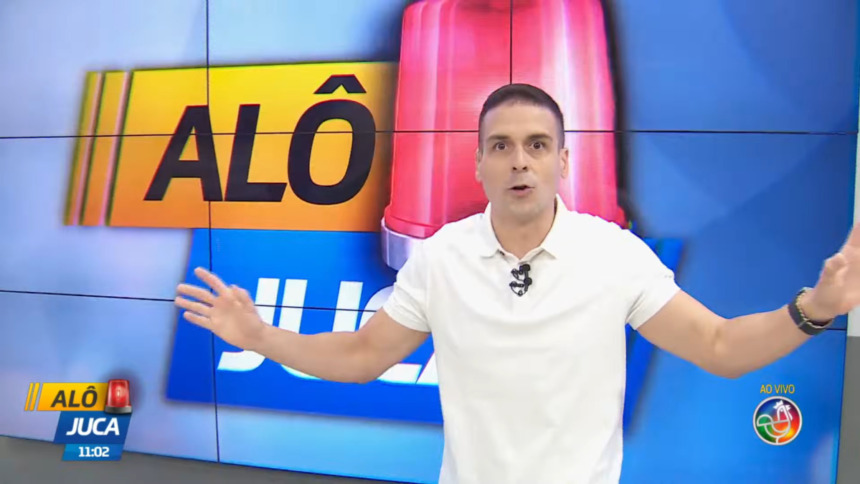 Marcelo Castro com os braços abertos, usando camisa branca, apresentando o Alô Juca na TV Aratu, SBT