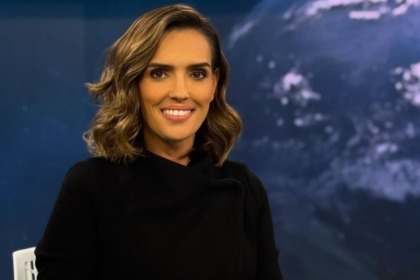Karyn Bravo sorridente em foto posada na bancada do Jornal da Cultura