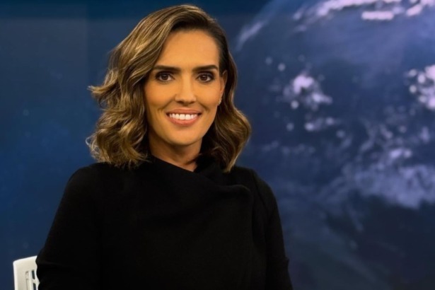 Karyn Bravo sorridente em foto posada na bancada do Jornal da Cultura
