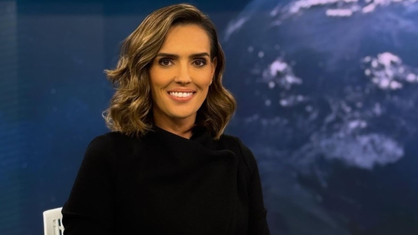 Karyn Bravo sorridente em foto posada na bancada do Jornal da Cultura