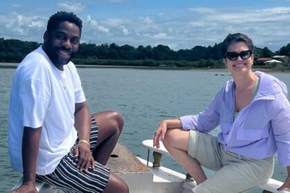 Ator Lázaro Ramos e jornalista Sandra Annenberg sorrindo em um barco, durante gravação externa para o programa Globo Repórter