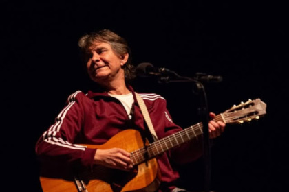 Lô Borges segura violão no palco de um show