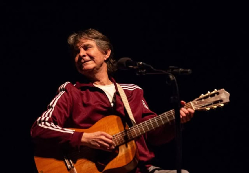 Lô Borges segura violão no palco de um show