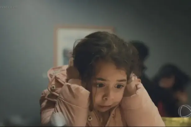 Turna/Meleke protagonista da novela mãe assustada e com as mãos no ouvido para não escutar briga de mãe e padrasto em cena do folhetim