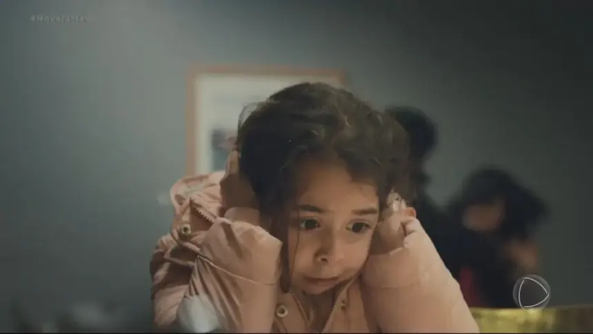 Turna/Meleke protagonista da novela mãe assustada e com as mãos no ouvido para não escutar briga de mãe e padrasto em cena do folhetim
