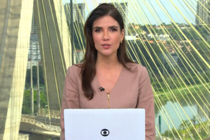 Jornalista Sabina Simonato apresentando o telejornal Bom Dia Brasil, com a Ponte Estaiada de São Paulo ao fundo e laptop à frente