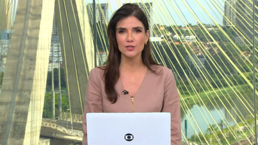 Jornalista Sabina Simonato apresentando o telejornal Bom Dia Brasil, com a Ponte Estaiada de São Paulo ao fundo e laptop à frente
