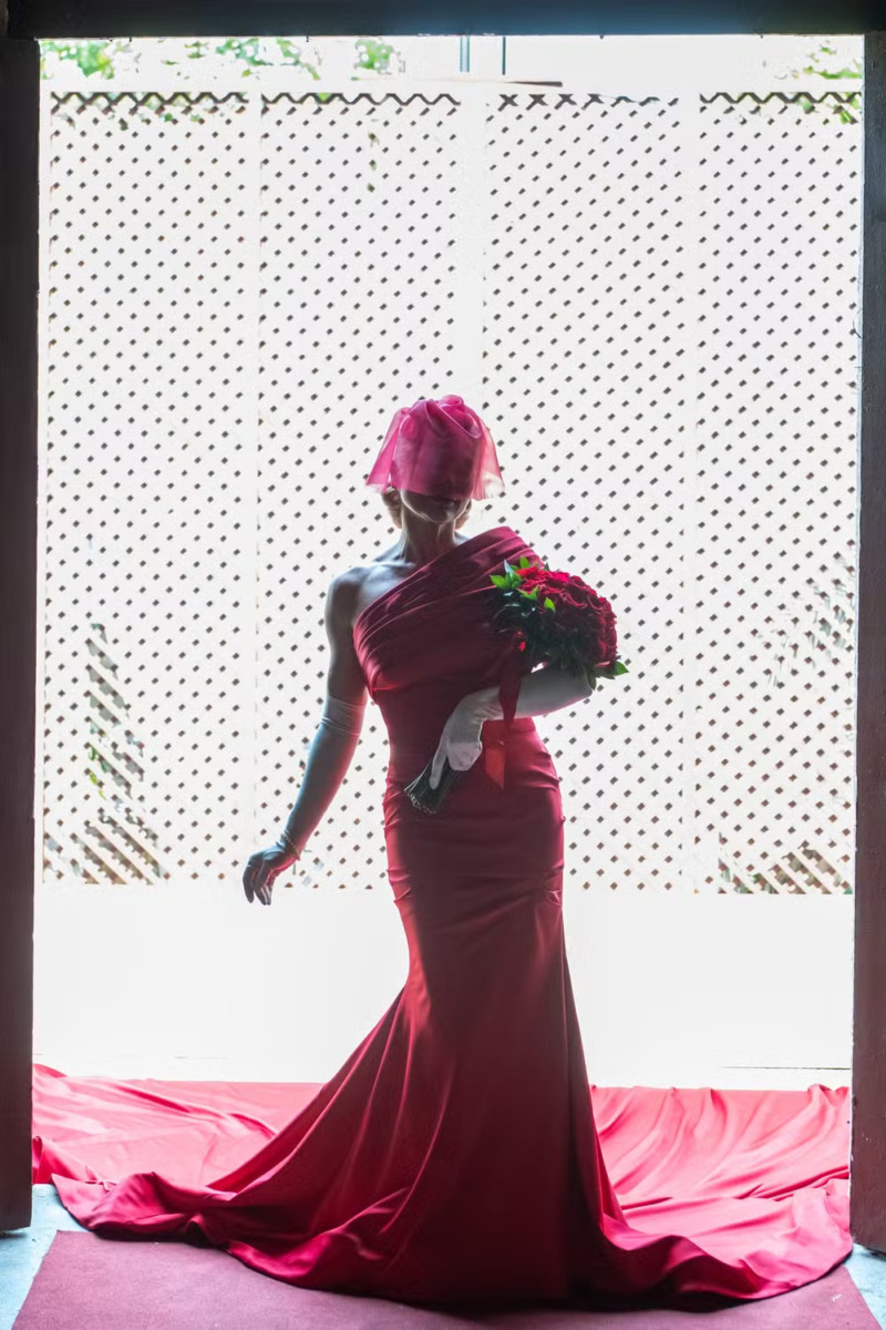 Sandra em pé com o vestido longo vermelho e uma longa calda. Ela está na porta da igreja em cena de Êta Mundo Melhor!
