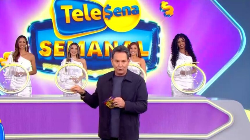 Luís Ricardo no centro do palco da Tele Sena Semanal. O cenário está temático na cor do bilhete lilás