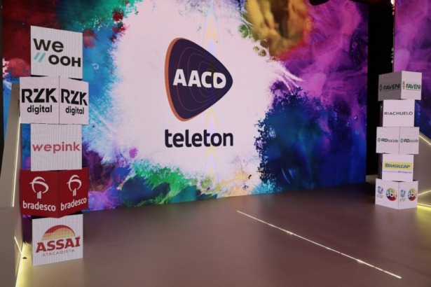 Palco do Teleton no SBT com o logo da ação no megatelão, ao lado caixas com as marcas patrocinadoras