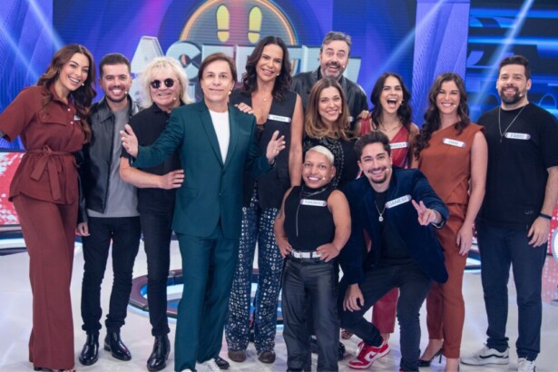 Tom Cavalcante e os 11 participantes famosos do programa de game show Acerte ou Caia, posando juntos no palco de luzes azuis