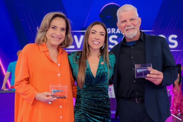 Apresentadora Patricia Abravanel com os atores Totia Meireles e Raul Gazolla, todos segurando troféus no palco do Programa Silvio Santos