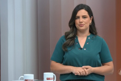 Raiane Brancatti de blusa verde em frente a bancada do TJ Aparecida