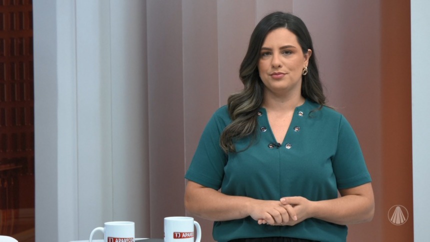 Raiane Brancatti de blusa verde em frente a bancada do TJ Aparecida