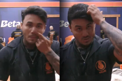 Wallas com o dedo dentro do nariz e passando a mão no cabelo