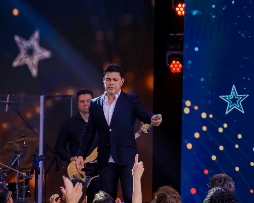 Zezé Di Camargo aponta o microfone para a plateia que assiste ao show especial de Natal no SBT