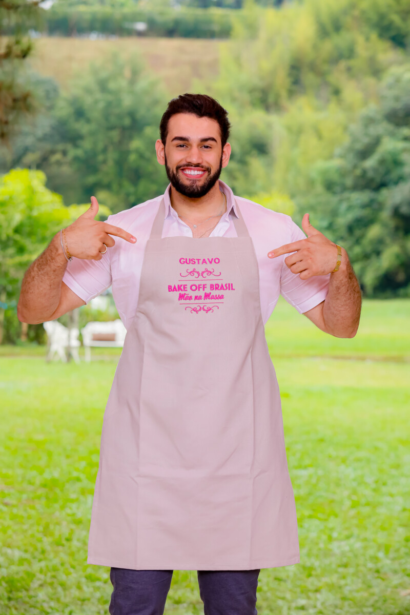 Gustavo aponta para o avental do Bake Off Brasil