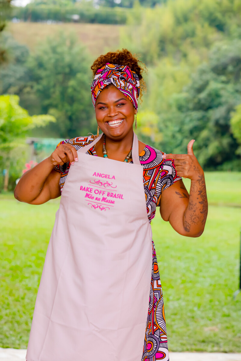 Angela aponta para o avental do Bake Off Brasil