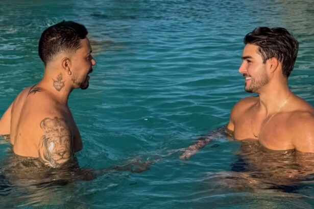 Carlinhos Maia e Lucas Lobato sem camisa e sorrindo frente a frente dentro de uma piscina