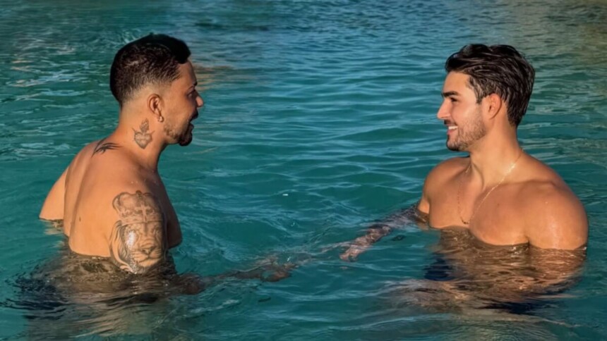 Carlinhos Maia e Lucas Lobato sem camisa e sorrindo frente a frente dentro de uma piscina