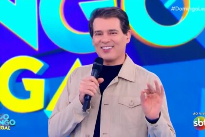 Celso Portiolli apresentando o Domingo Legal em frente ao telão com o logo do programa