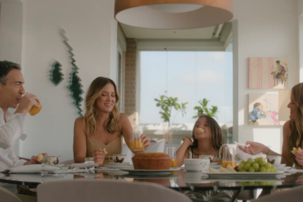Cesar Tralli, Ticiane Pinheiro, Rafaela e Manuela sentados em uma mesa, em trecho da Vinheta de Fim de Ano da Globo