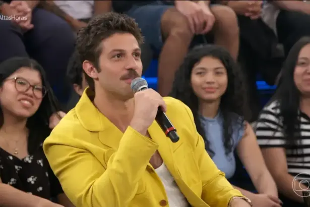 Chay Suede de blase amarelo sorrindo no cenário do Altas Horas onde falou sobre sua próxima novela das 9