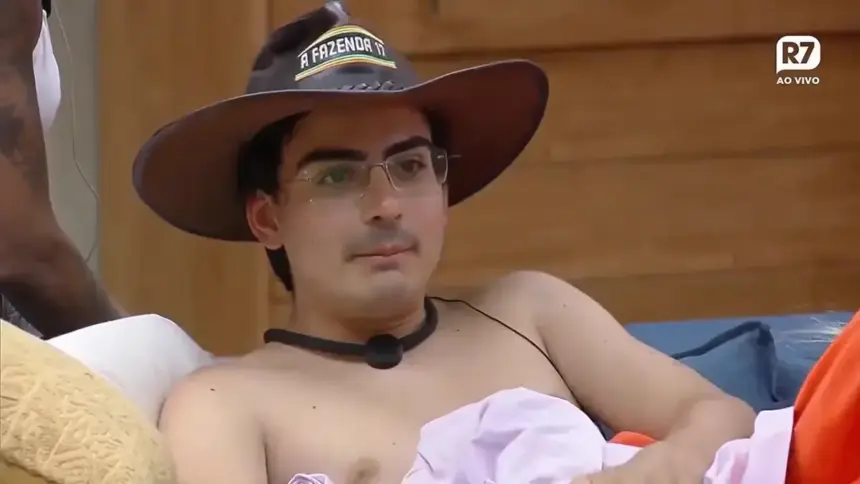 Dudu Camargo com chapéu de fazendeiro na cabeça e sem camisa na sala de A Fazenda
