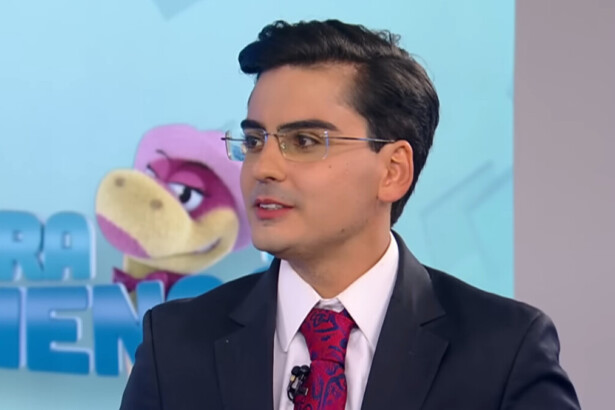 Dudu Camargo, de terno e gravata, em trecho de participação no cenário do Balanço Geral na RECORD