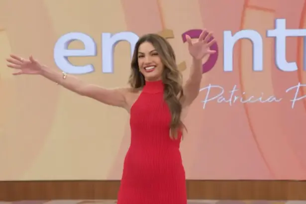 Patricia Poeta abre os braços em frente ao telão com o logo do programa Encontro
