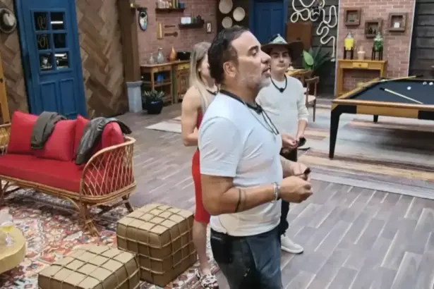 Fabiano com dardo na mão para atirar na foto de Duda dentro do Rancho do Fazendeiro em A Fazenda 17
