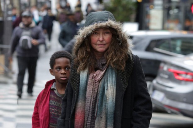 Mulher com roupa de frio caminha na frente de uma criança negra pelas ruas de Paris em cena do filme Sob as Escadas de Paris, da TV Aparecida