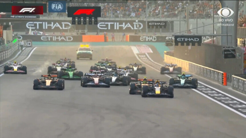 Carros da Fórmula 1 na pista do GP de Abu Dhabi na transmissão da Band com o logo da emissora posicionado no canto superior da tela