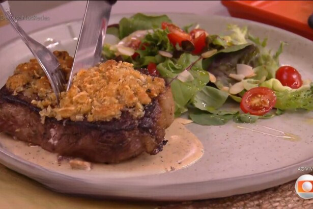Bife de chorizo com crosta de ervas no prato branco do É de Casa, acompanhado de uma salada