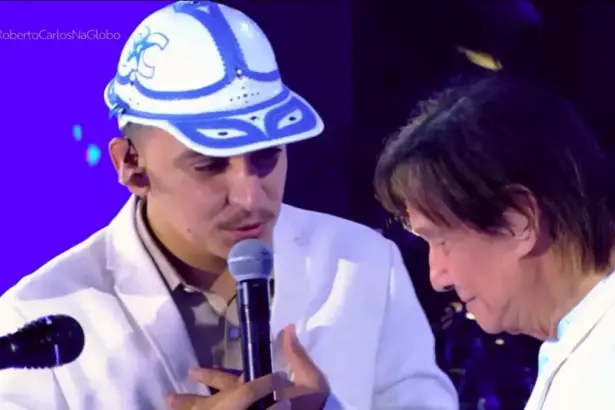 João Gomes canta com a mão no peito em frente a Roberto Carlos