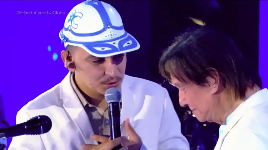 João Gomes canta com a mão no peito em frente a Roberto Carlos