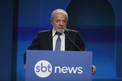 Lula discursa no púlpito com o logo do SBT News