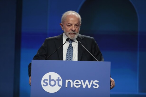 Lula discursa no púlpito com o logo do SBT News