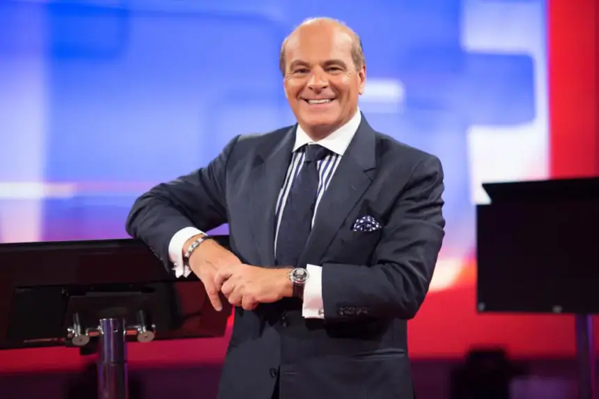 Marcelo de Carvalho sorridente com o braço encostado na bancada do seu programa na redeTV!