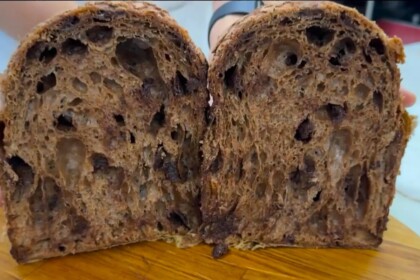 Panetone com cobertura de amêndoas e cacau aberto em cima de uma tábua de madeira no Mais Você