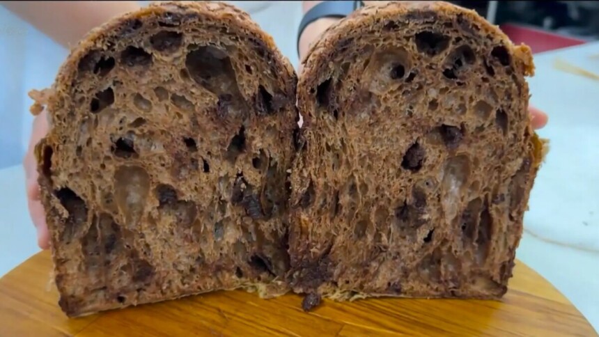 Panetone com cobertura de amêndoas e cacau aberto em cima de uma tábua de madeira no Mais Você