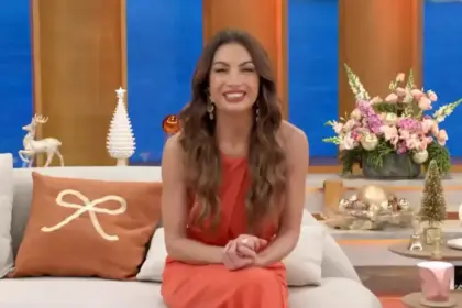 Patrícia Poeta sentada no sofá do programa Encontro. Ela está sorridente e de vestido marrom
