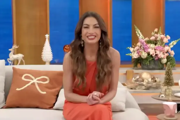 Patrícia Poeta sentada no sofá do programa Encontro. Ela está sorridente e de vestido marrom