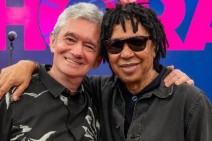 O apresentador Serginho Groisman e o cantor Djavan se abraçando e sorrindo no estúdio do programa Altas Horas, em close-up