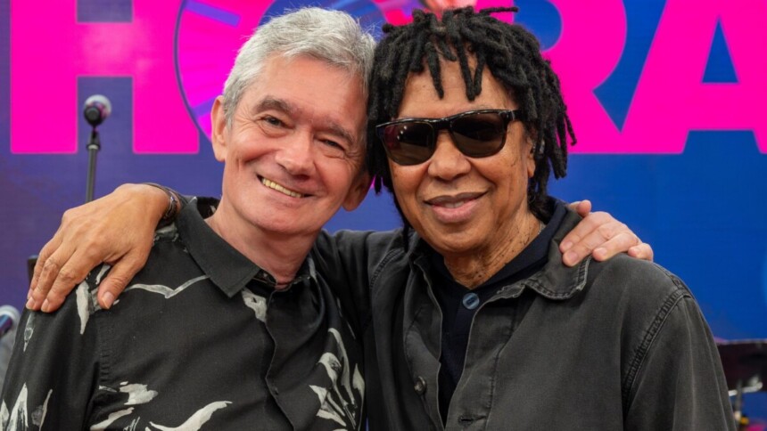 O apresentador Serginho Groisman e o cantor Djavan se abraçando e sorrindo no estúdio do programa Altas Horas, em close-up
