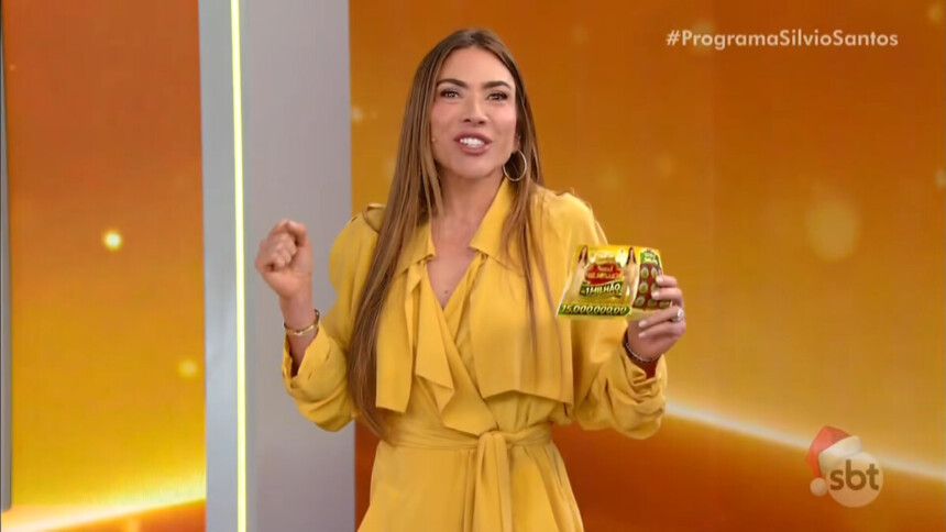 Patricia Abravanel sorrir e segura o bilhete da Tele Sena de Natal no 4º sorteio